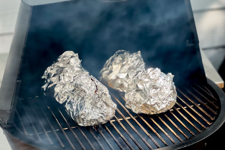 cabbage quarters wrapped in foil on the smoker