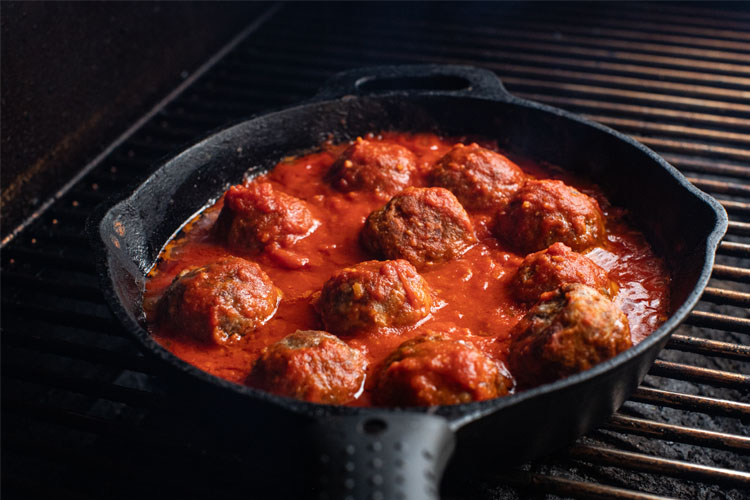 cooked meatballs in marinara sauce in a skillet on the smoker
