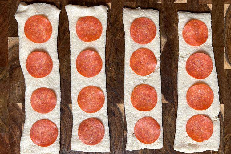 pepperoni slices down the length of the pizza dough