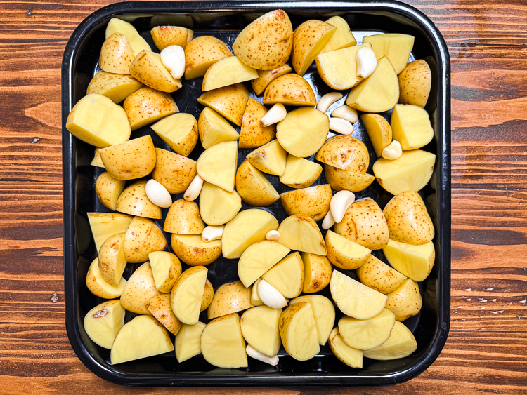 uncooked potatoes and garlic in an oven tray