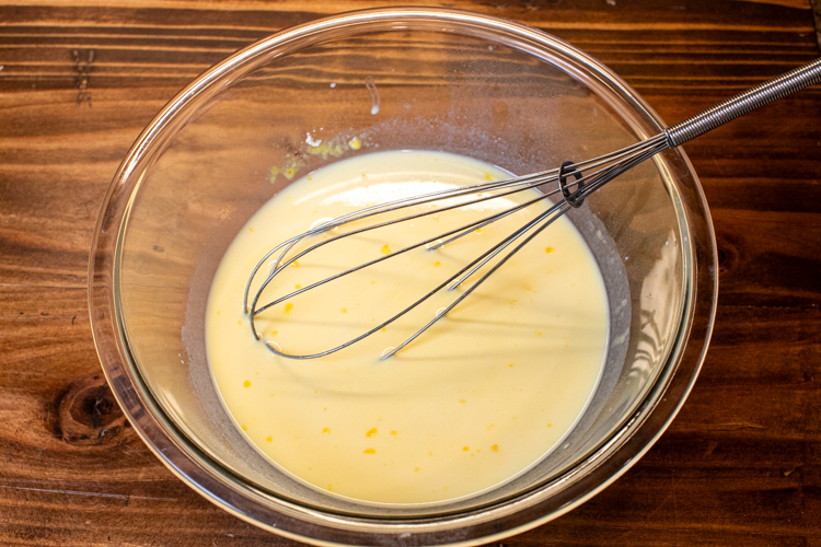 a glass bowl with instant pudding and a whisk in it