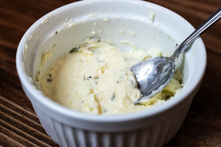 compound butter in a white bowl with a spoon in it