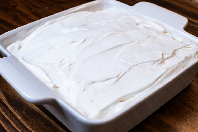 a baking dish with banana pudding covered in cool whip