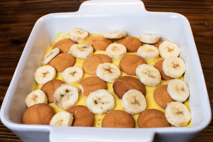 a baking dish with a layers of pudding, banana slices and nilla wafers in it