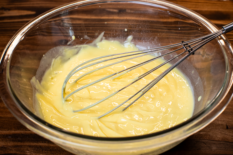 a glass bowl with instant pudding in it and a whisk