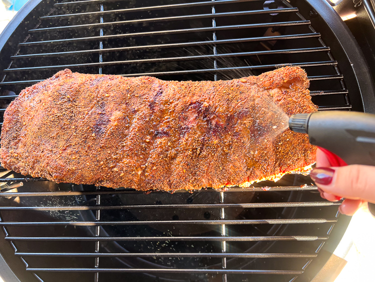 ribs on the smoker being spritzed