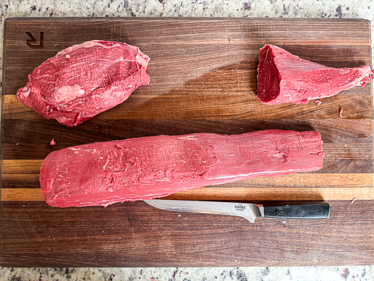 beef tenderloin with the ends cut off on a wooden chopping board