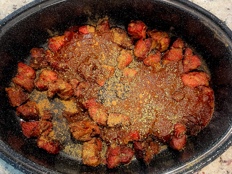 pork, chili sauce oregano in a large black pot