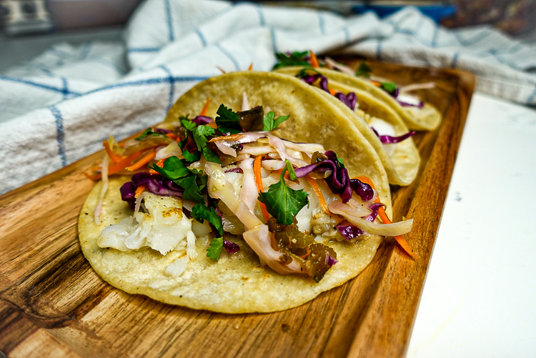 a wooden board with white fish and pineapple and jalapeno slaw on it