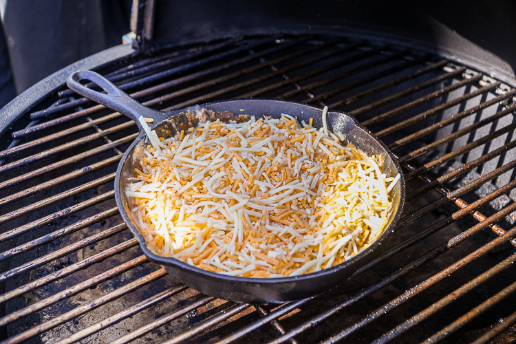 chili cheese dip with unmelted cheese on top in the smoker