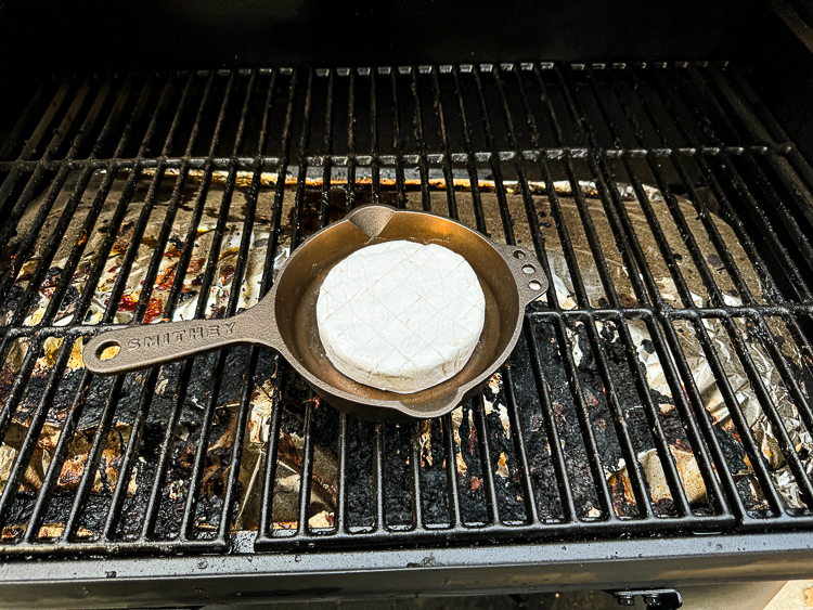wheel of brie in a cast iron pan in the smoker