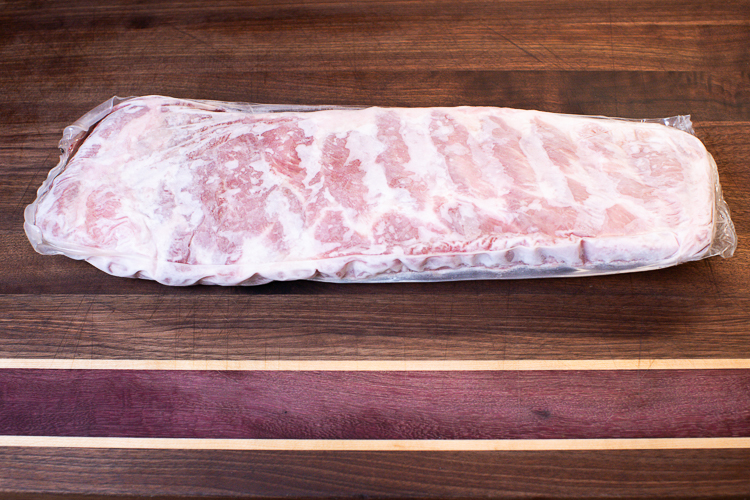 frozen rack of pork ribs on a wooden board