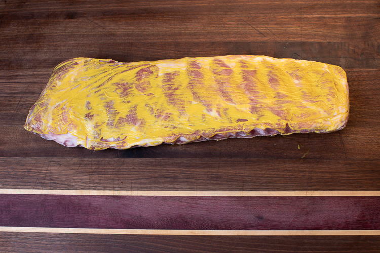 frozen pork rib with mustard binder on a wooden board