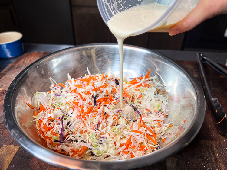 bowl of slaw with dressing being poured on it