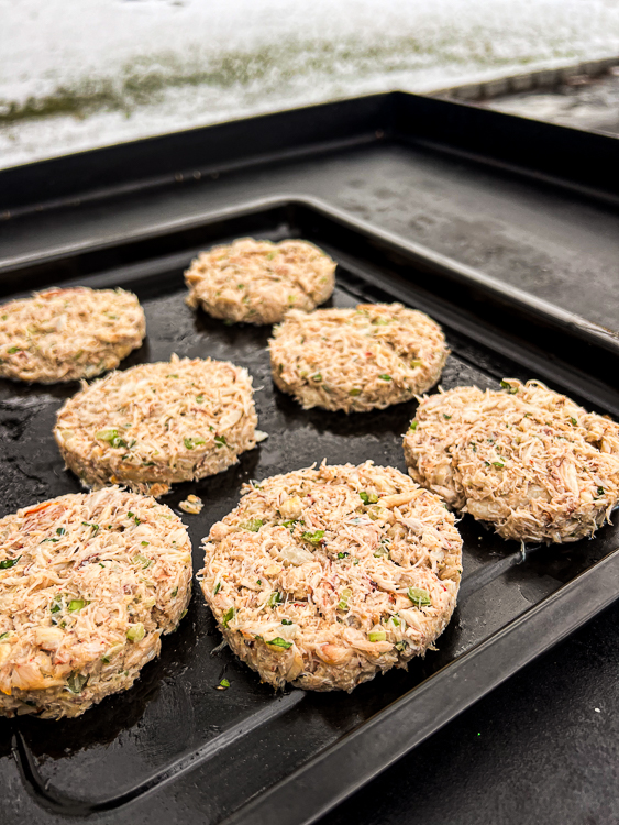 uncooked crab cakes on a metal baking tray