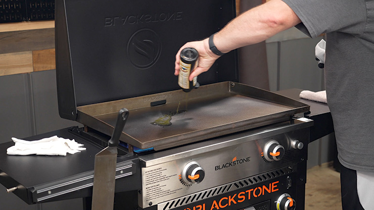 a man seasoning Blackstone 28 Griddle with flaxseed oil