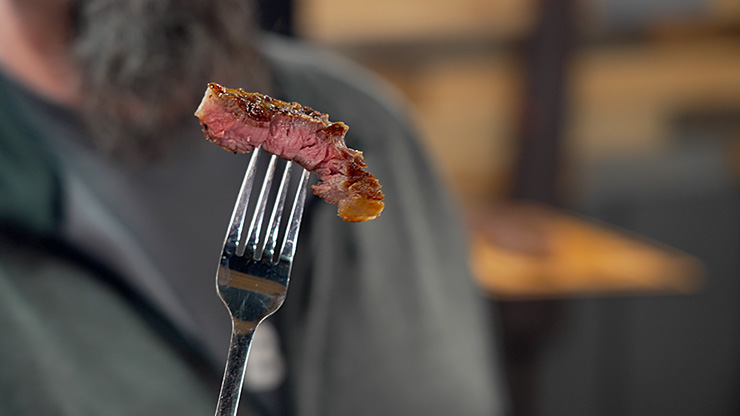 a piece of medium rare ribeye steak on a fork