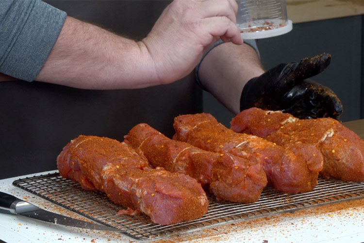 raw pork tenderloins being seasoned