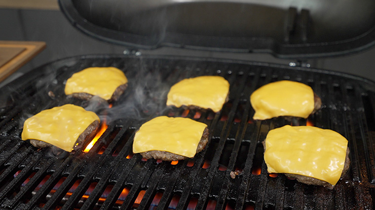 burger patties with cheese cooking on the Weber Q+