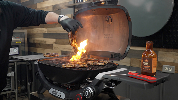 a person cooking meat on the Weber Q+