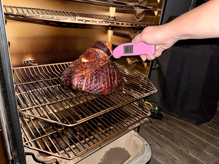 taking the temperature of smoked ham in the smoker