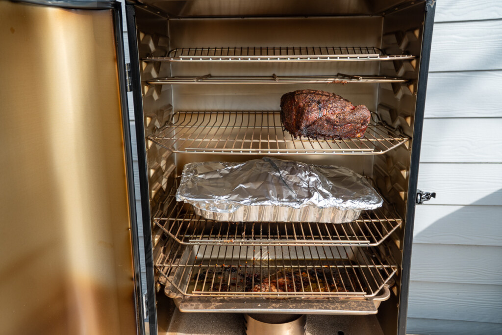 covered aluminum tray on a shelf in the smoker