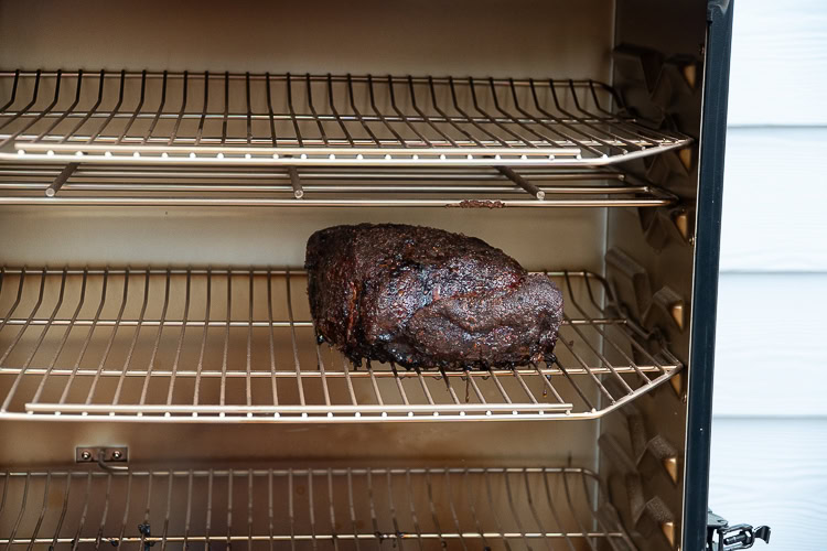 cooked piece of pork butt on a shelf in the smoker