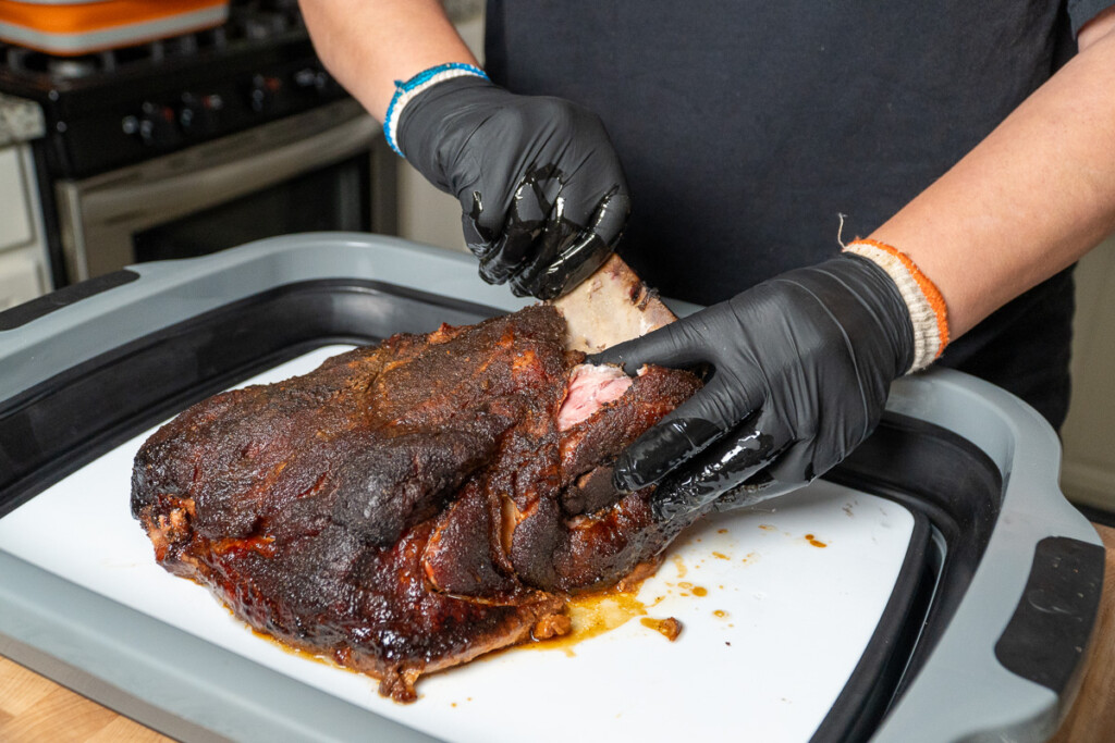 bone being pulled out of smoked pork butt by black gloved hand