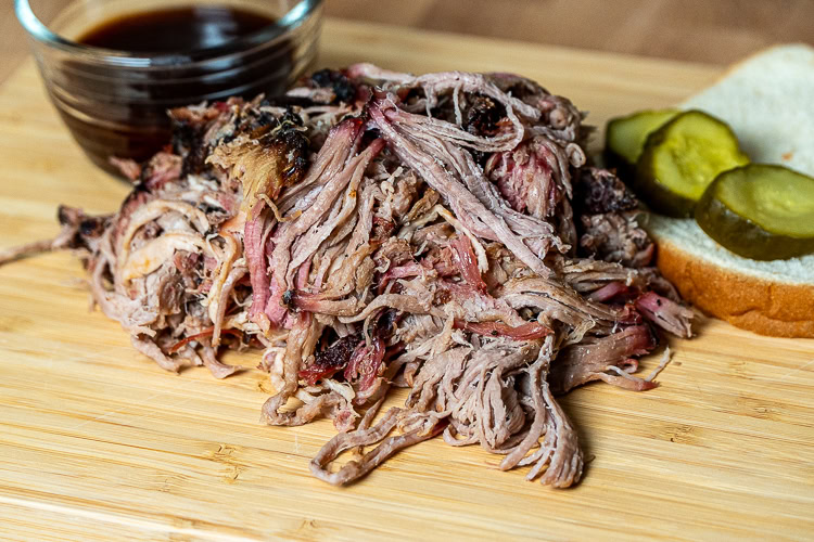 a pile of shredded pulled pork on a wooden board