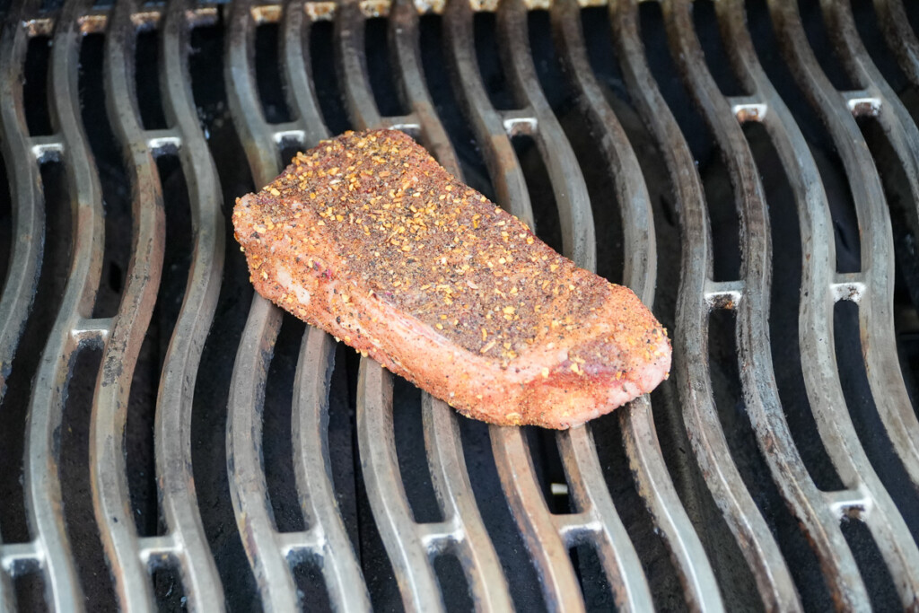 seasoned raw steak on the grill