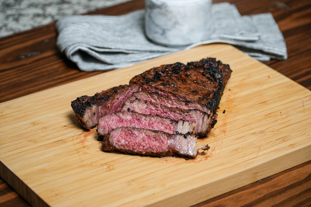 sliced new york strip steak on a wooden board