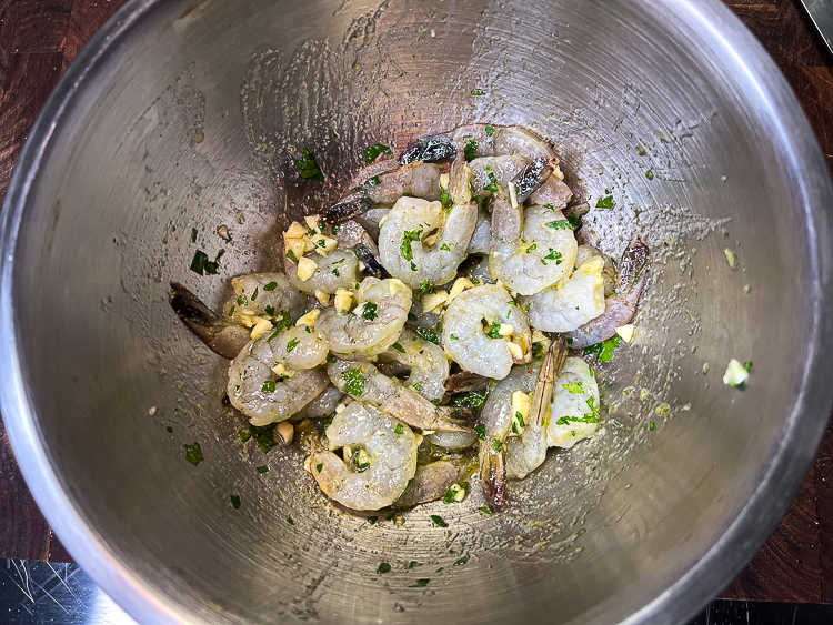 raw shrimp marinating in a metal bowl