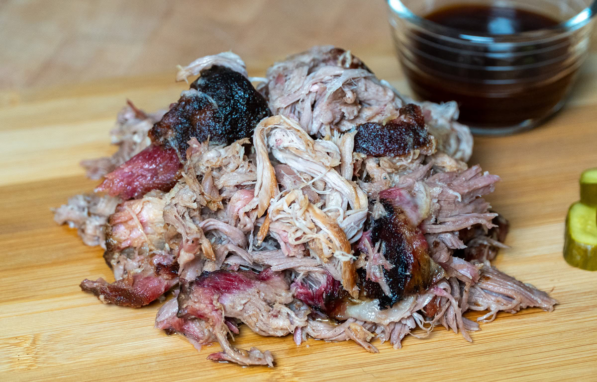 pellet grill pulled pork in a pile on a wooden board