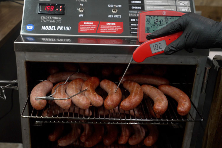 sausage in the smoker with a temperature probe in one reading 102 degrees