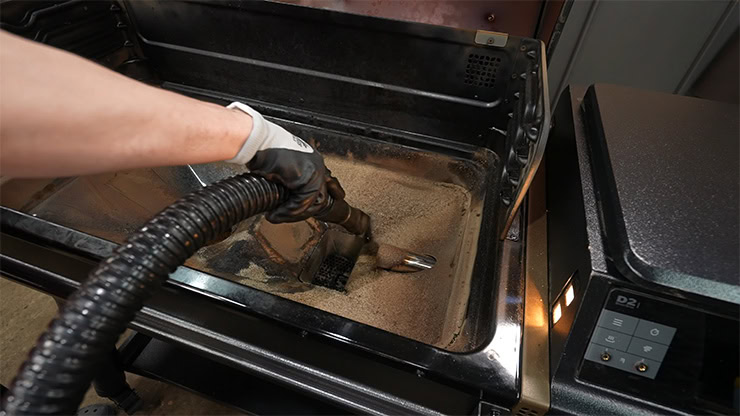 a person vacuuming the ash from the Traeger Ironwood pellet grill