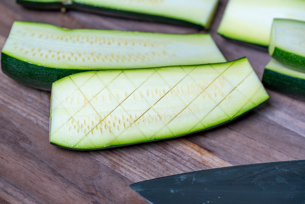 raw zucchini with a cross hatch pattern sitting on a wooden board