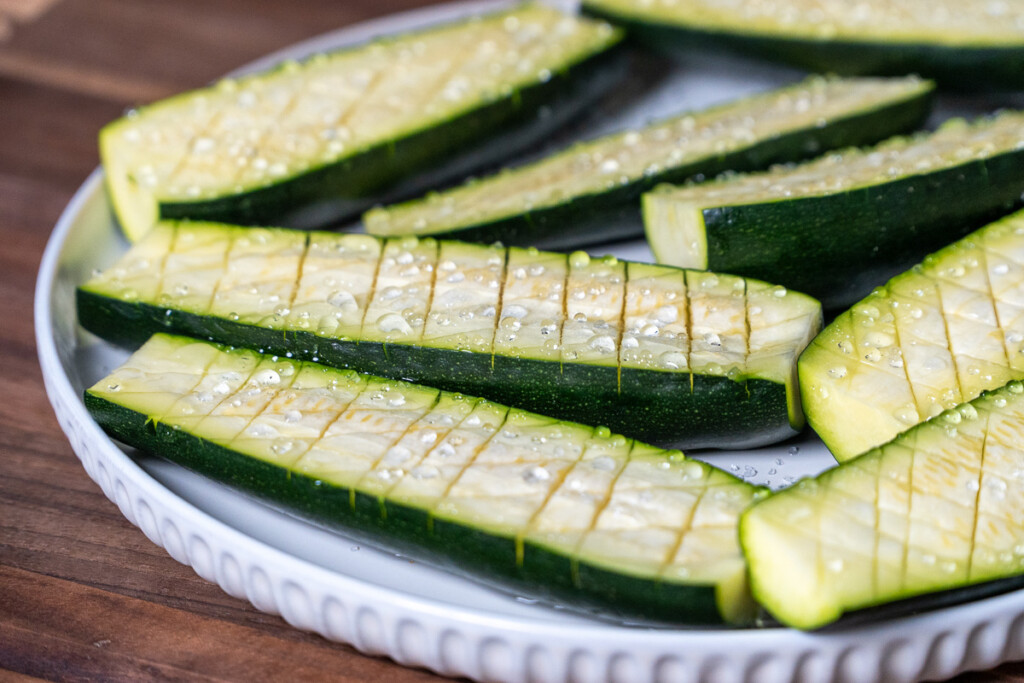 raw zucchini sweating out water sitting on a white plate