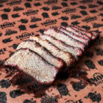 Smoked chuck roast sliced like brisket with visible smoke ring and bark on butcher paper