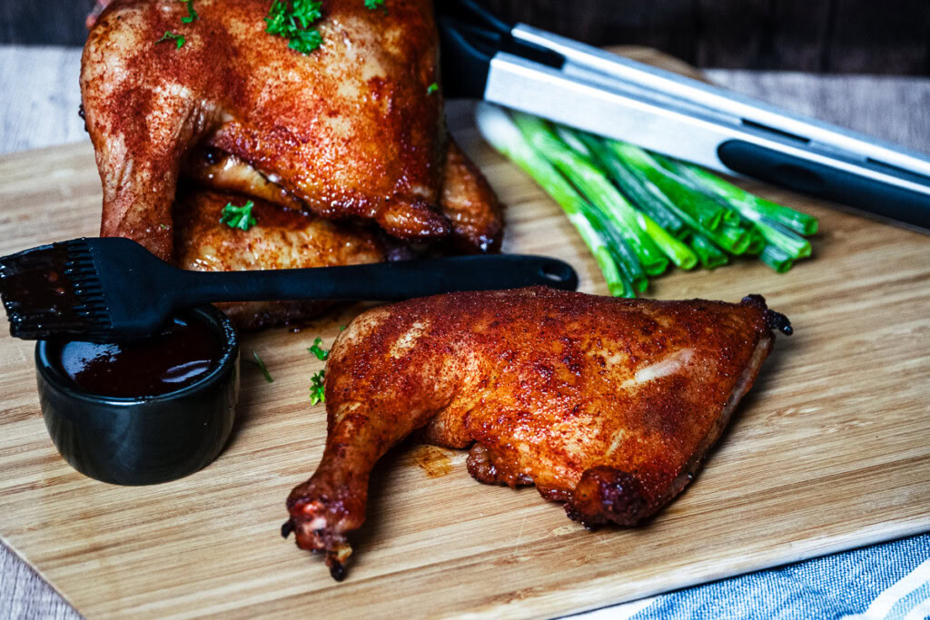 cooked smoked chicken quarters presented on on a wooden with garnish
